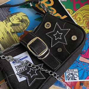 Detail of star denim shoulder bag with silver chain strap and metal buckle accent