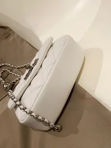 Detail view of the white quilted leather side and silver chain of this crossbody bag