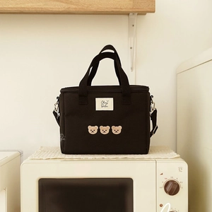 Detail of black canvas lunch bag featuring three embroidered bears and Chez Bébé label