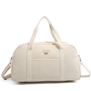 Detail of cute bear embroidery and reinforced canvas handles on the cream mommy bag