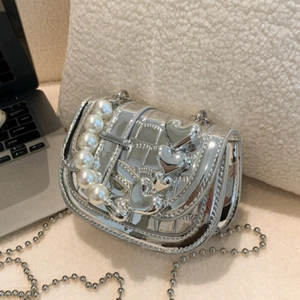 Silberne Metallic-Miniumhängetasche mit Perlengriff und Herz-Anhängern auf Tisch
