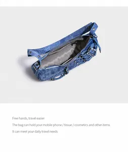 Detail of blue denim shoulder bag with metal buckles, studs and spacious inner lining