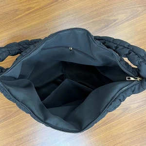 Detailed interior of black quilted cloud tote bag with zipper pocket and compartments
