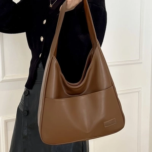 Brown large capacity faux leather tote bag with front pocket shown on shoulder