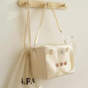Close-up of cream canvas mommy bag with bear embroidery and secure zipper closure