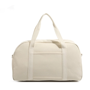 Detailed view of cream canvas diaper bag featuring sturdy double handles and front pocket