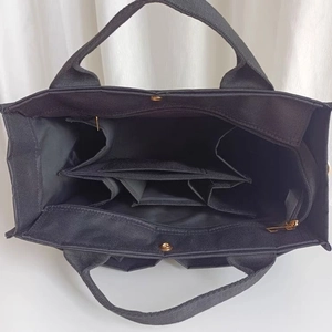 Detail view of the multi-compartment interior with gold clasp and zipper on black tote