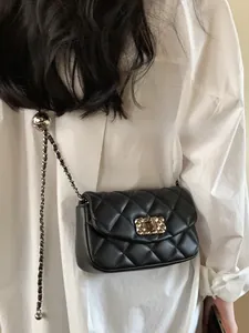 Chic quilted black chain crossbody bag worn by a model in a white shirt detail