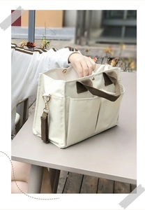 Detailed view of canvas tote bag with multi-pocket design and brown handles for mothers