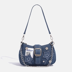 Detailed close-up of blue denim shoulder bag featuring a star patch and large metal buckle
