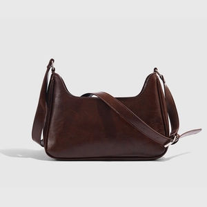 Makro-Detail der dunkelbraunen, glänzenden Hobo-Tasche mit verstellbarem Gurt und Silberbeschlag