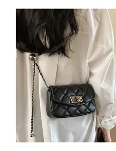 Detail of black quilted leather crossbody bag with gold metal chain and ball buckle