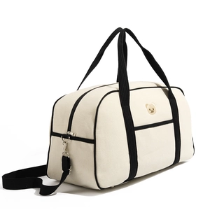 Detail of canvas baby bag featuring cute bear embroidery and contrast black handles