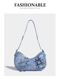 Detail of washed blue denim half-moon bag with vintage motorcycle belts and silver buckles