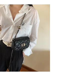 Detail of black quilted crossbody bag with golden chain strap and adjustable metal ball