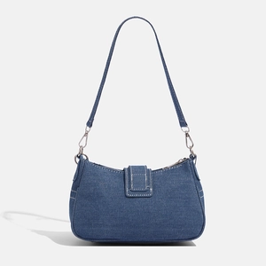 Detailed macro view of dark blue washed denim shoulder bag with silver hardware and stitching