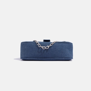 Close-up of blue denim shoulder bag featuring a silver metal chain and star hardware