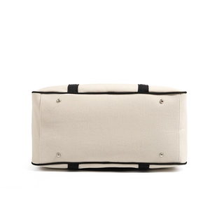 Detail view of the canvas bag bottom showing black trim and four silver metal studs