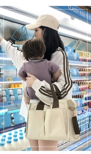 Close-up of multi-pocket canvas mommy bag with brown handles in a grocery setting