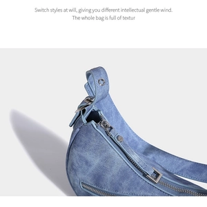Detailed close-up of blue denim texture and silver zipper on saddle shoulder bag