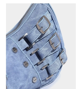 Close-up of light blue denim shoulder bag with silver metal buckles and Y2K rivets