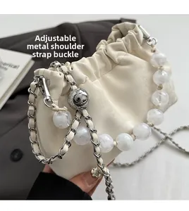 Detail der Silberkette und Perlenakzente an einer weißen Plissee-Tasche mit Schnalle
