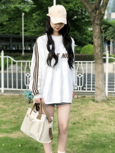 Close-up of white canvas tote bag with brown straps and multi-compartment design