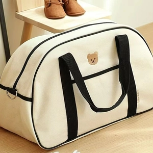 Large capacity canvas mommy bag with bear embroidery and black trim on wooden floor