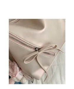 Detail of pink bow leather zipper puller and silver metallic zipper on the backpack