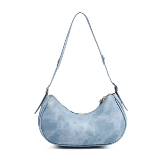 Close-up of light blue denim crescent underarm bag with washed texture and silver hardware