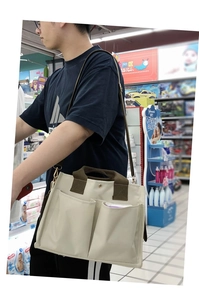 Detail of canvas bag with multi-pockets, olive green handles and adjustable shoulder strap