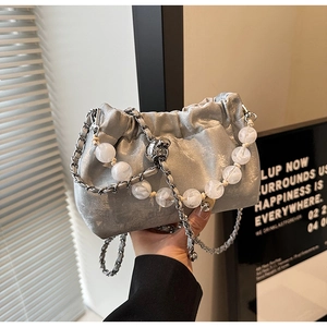 Detail der silbernen Falten-Cloud-Bag mit Perlenkette und Liquid-Metal-Struktur