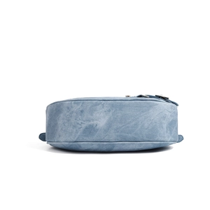 Detailed bottom view of blue denim crescent bag with metallic buckle and fine stitching