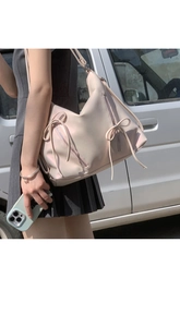 Elegant large pink bow shoulder bag with glossy finish shown on model outdoors