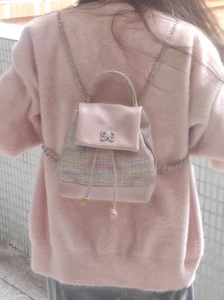 Detail of pink woven mini backpack featuring a silver butterfly buckle and chain strap