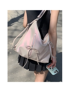 Detail of soft pearlescent white tote bag with bow accents and metal zipper on the side