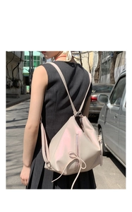 Detail of a pearl white bow backpack featuring geometric structure and soft iridescent finish