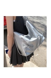 Silver metallic hobo bag with bow ribbon and zipper details shown in a street style view