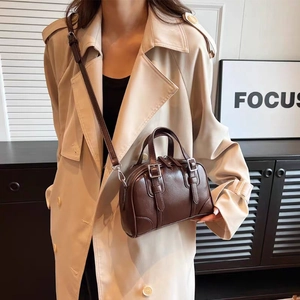 Detailed macro view of dark brown textured leather crossbody bag with silver buckles