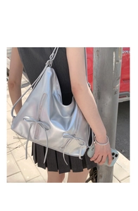 Detail of silver metallic hobo bag featuring decorative bows and vertical zippers