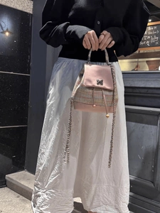 Pink tweed and leather backpack with silver bow clasp and chain strap held by model