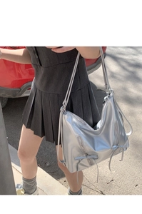 Close-up of metallic silver tote bag with decorative zippers and delicate bow details