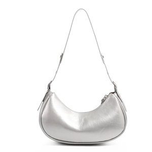 Detail of silver metallic crescent shoulder bag with smooth curved lines and thin strap