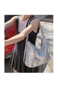 Detail shot of silver PU leather tote bag featuring bow accents and zipper pockets