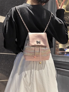 Pink tweed mini backpack with chain strap and metal butterfly on a model back view