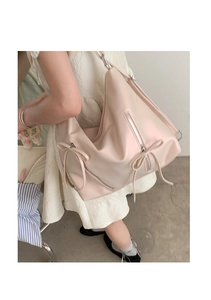 Close-up of light pink tote bag featuring a decorative bow tie and soft glossy texture