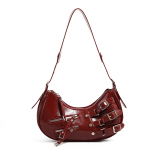 Detail of dark red semi-moon motorcycle bag with silver buckles and Y2K metal studs
