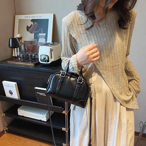 Detail of a vintage black leather bowling bag with twin buckle straps and crossbody style