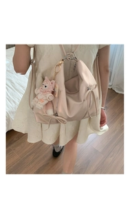 Pink bow backpack with plush fox charm shown in a cozy home setting close-up view