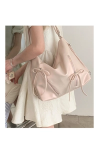 Detail of soft beige PU leather tote bag with decorative bows and zippers on a model
